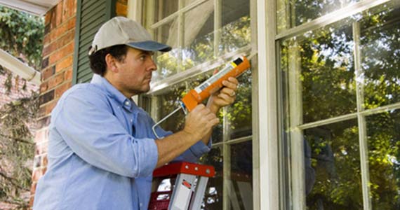 un vitrier en train de poser des joints sur une vitre fenetre
